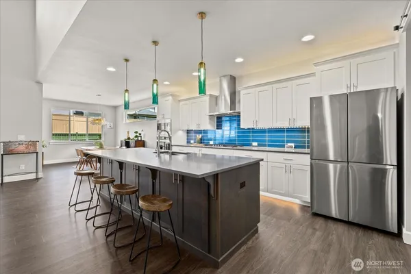 a kitchen with stainless steel appliances granite countertop a table chairs stove and refrigerator
