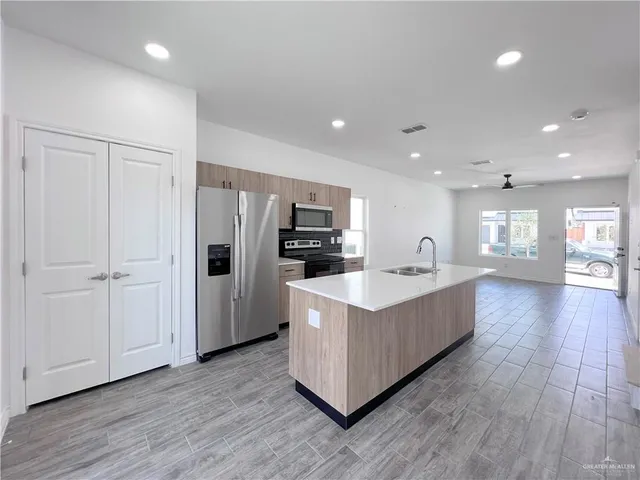 a large white kitchen with a large counter top and stainless steel appliances