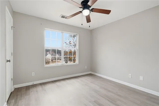 an empty room with a window and a fan