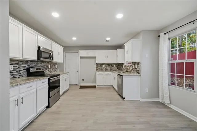 a kitchen with white cabinets and stainless steel appliances