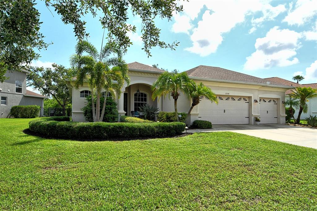12358 Lavender Loop Bradenton, FL 34212 - Photo 1 of 1 a view of a white house with a big yard and potted plants and a large tree