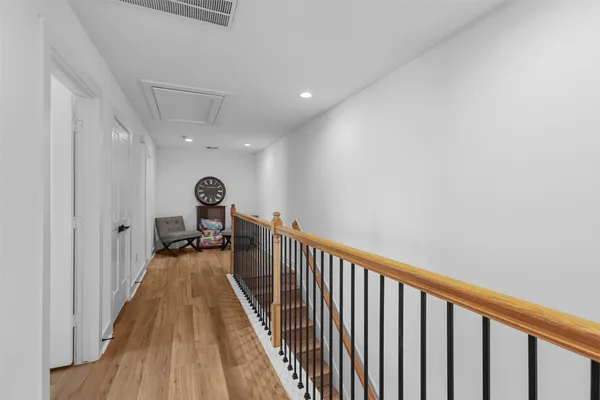 a view of a hallway with wooden floor and stairs