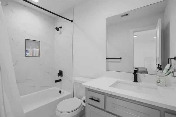 a bathroom with a sink a toilet a mirror a bathtub and shower