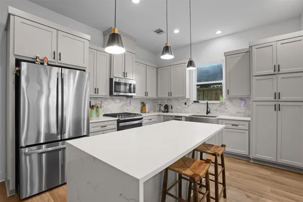 a kitchen with refrigerator a stove a sink and white cabinets