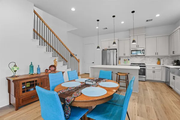 a dining room with furniture a wooden floor and kitchen view