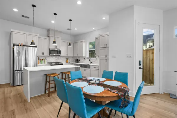 a kitchen with a dining table chairs refrigerator and microwave
