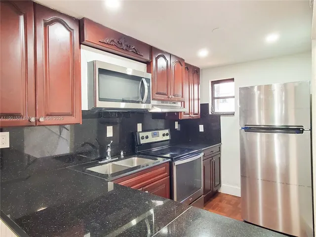 a kitchen with stainless steel appliances granite countertop a refrigerator a stove a sink and a microwave