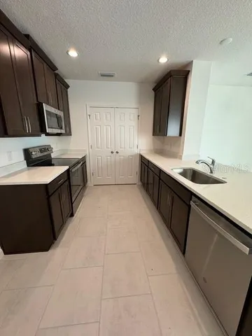 a large kitchen with stainless steel appliances a sink dishwasher stove and cabinets