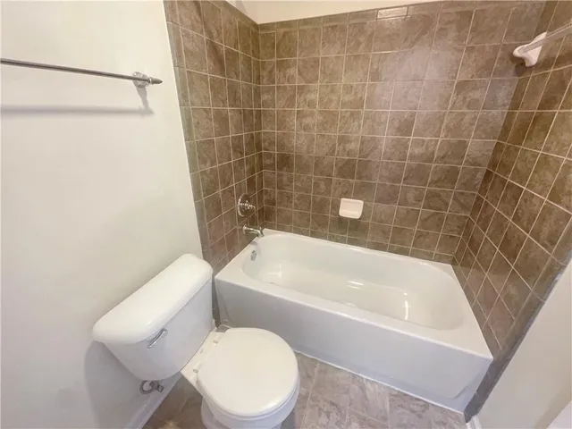 a white toilet sitting next to a bath tub