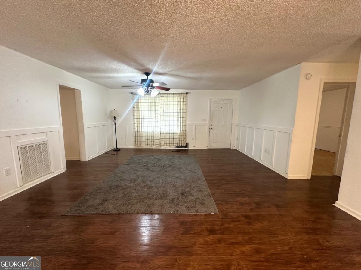 1296 Boone Road Adel, GA 31620 - Photo 4 of 20 an empty room with wooden floor and staircase