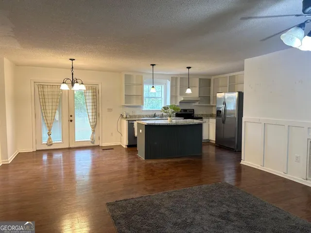 a kitchen with stainless steel appliances granite countertop a refrigerator a sink dishwasher a stove with wooden floor and cabinets