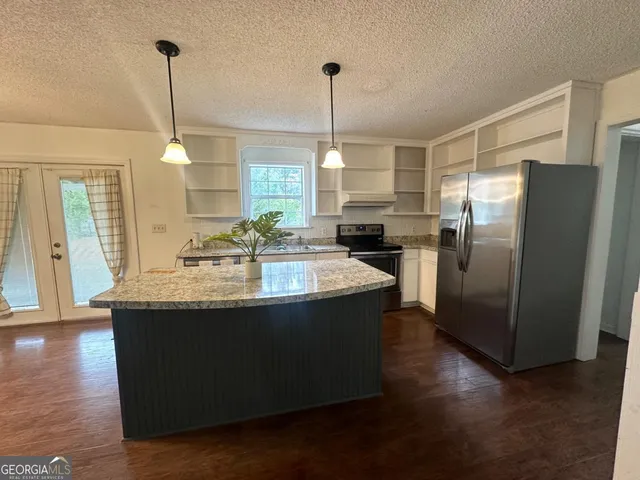 a kitchen with stainless steel appliances granite countertop a sink a refrigerator and a wooden floor