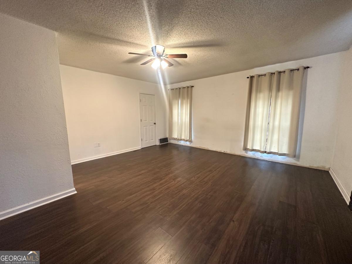 1296 Boone Road Adel, GA 31620 - Photo 7 of 20 an empty room with wooden floor chandelier fan and windows