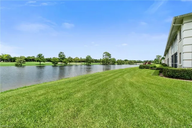 a view of a lake with a big yard and large trees