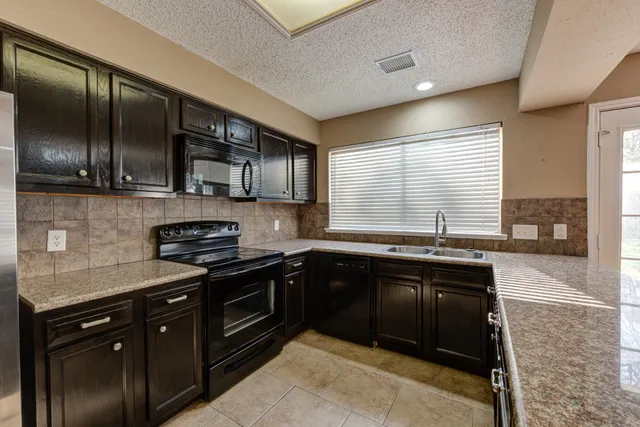 a kitchen with stainless steel appliances granite countertop wooden cabinets a sink and a stove