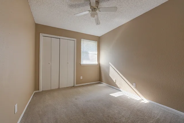 an empty room with windows and fan