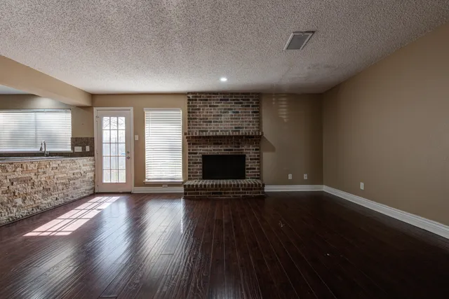 an empty room with wooden floor and fireplace