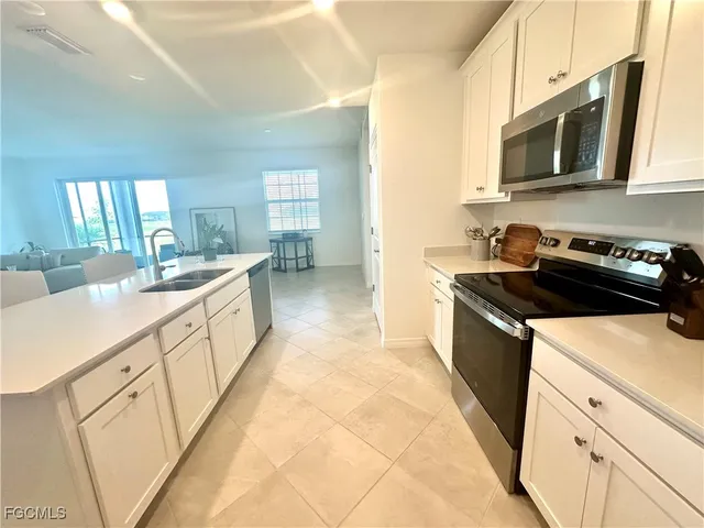 a kitchen with sink a microwave and cabinets
