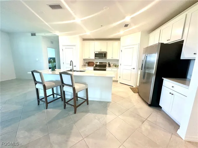 a kitchen with stainless steel appliances a refrigerator a stove a sink a dining table and chairs