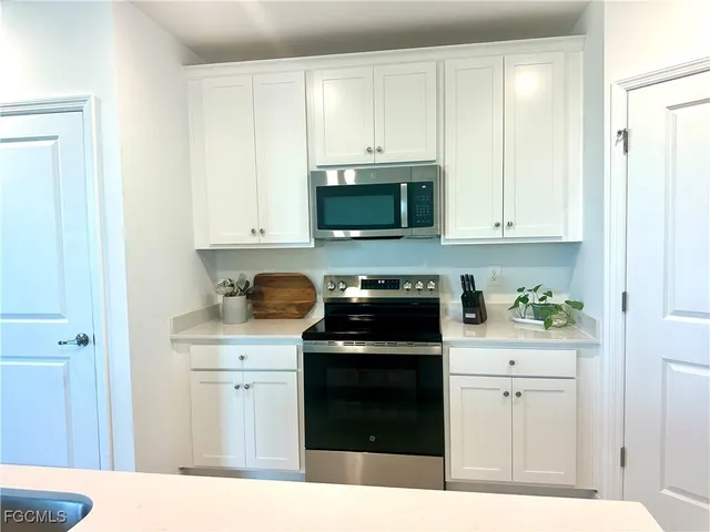 a kitchen with granite countertop white cabinets and stainless steel appliances