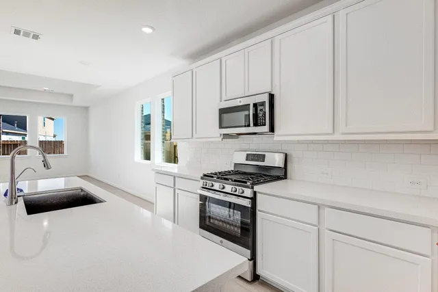 a kitchen with granite countertop a sink a stove and microwave
