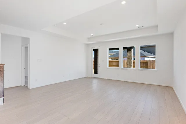 a view of an empty room with window and wooden floor