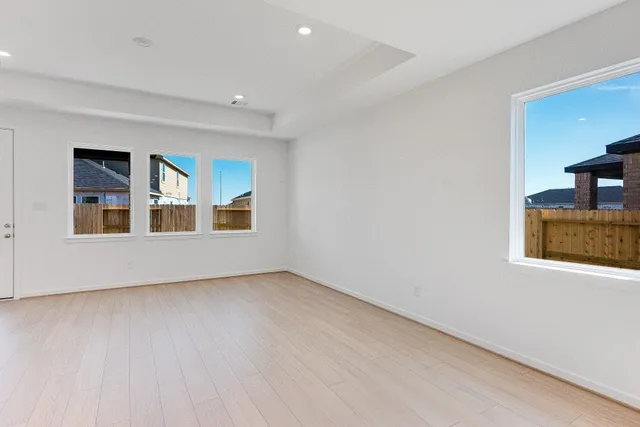 a view of an empty room with window and wooden floor