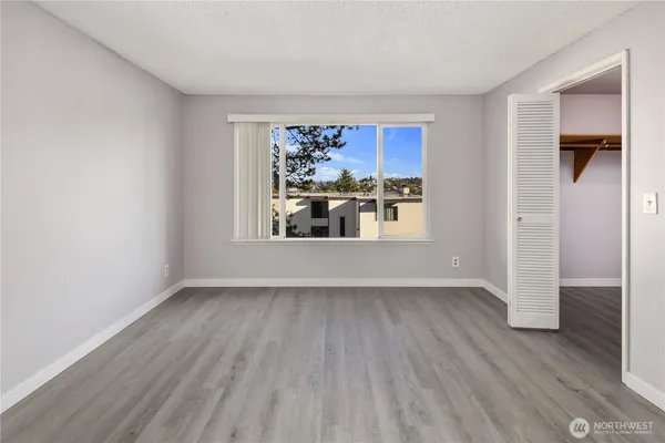 an empty room with wooden floor and windows