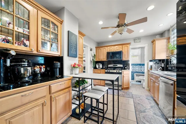 a kitchen with stainless steel appliances kitchen island granite countertop a stove top oven a sink a dining table and chairs with wooden floor