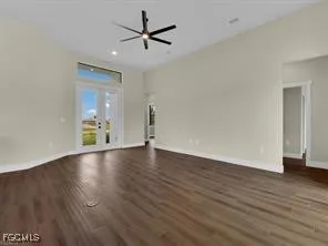 a view of an empty room with wooden floor and a ceiling fan