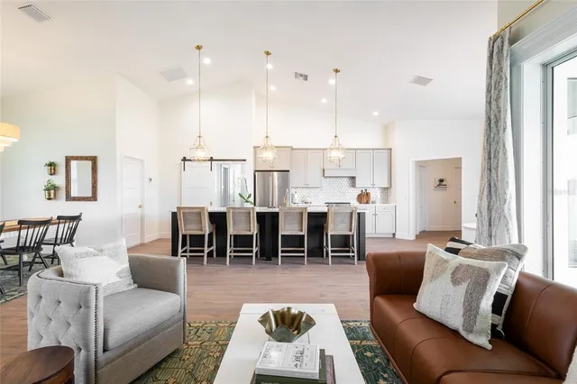 a living room with furniture kitchen view and a large window