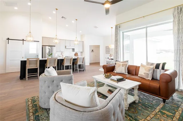 a living room with furniture kitchen view and a large window