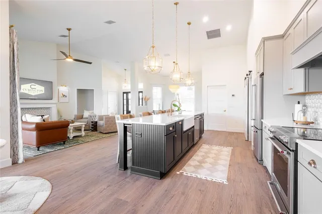 a kitchen with stainless steel appliances granite countertop a stove a sink dishwasher a refrigerator and a dining table with wooden floor