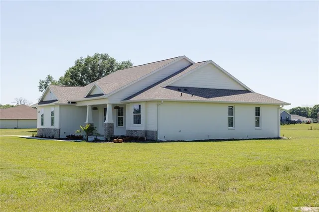 a front view of house with yard and trees in the background