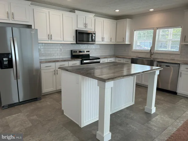 a kitchen with stainless steel appliances granite countertop a sink stove refrigerator and microwave