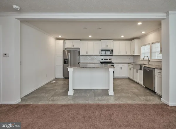 a kitchen with stainless steel appliances granite countertop a stove top oven a sink and a refrigerator
