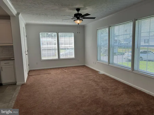 an empty room with chandelier fan and windows