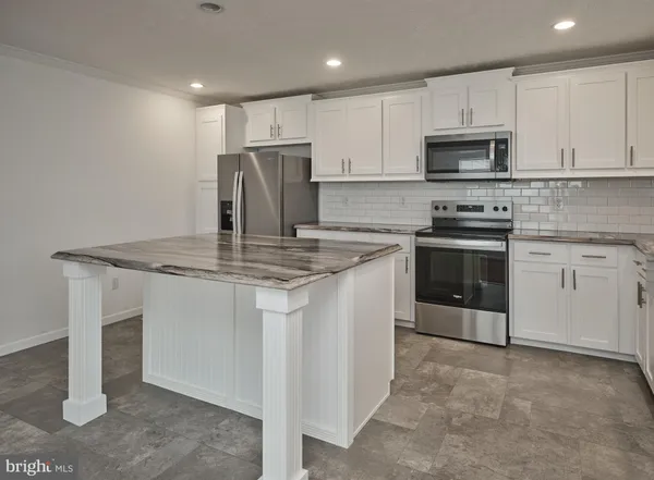 a kitchen with kitchen island granite countertop a stove sink and microwave