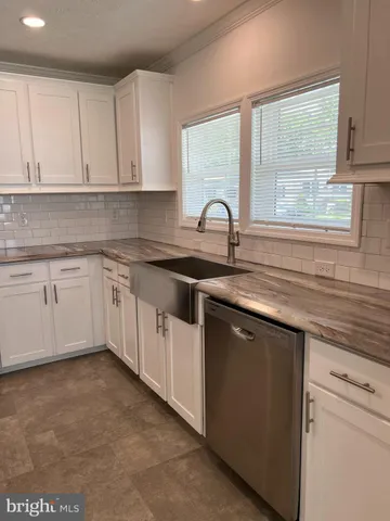 a kitchen with white cabinets appliances a sink and a window