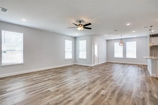 a view of an empty room with window and wooden floor