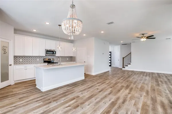 a open kitchen with kitchen island white cabinets and stainless steel appliances