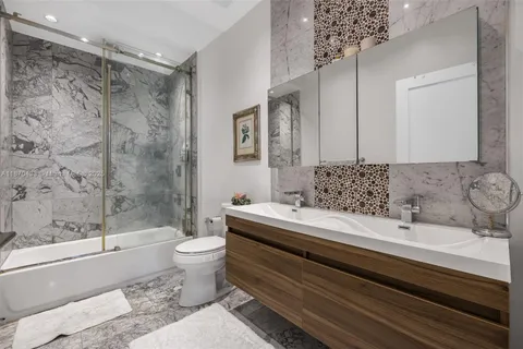 a bathroom with a granite countertop sink a toilet a mirror and bathtub