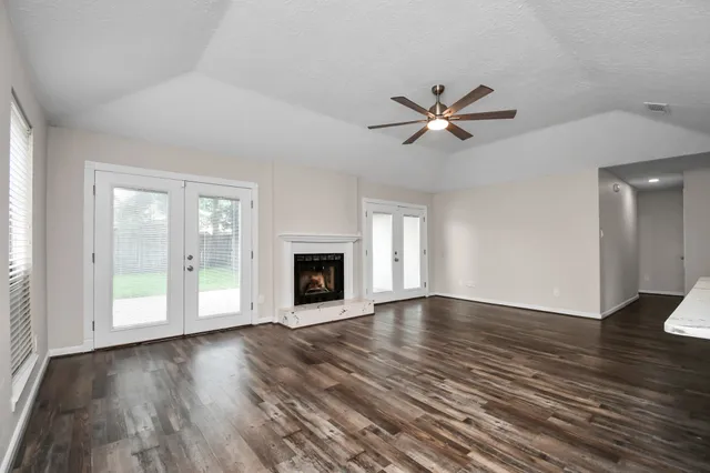 a view of a livingroom with a fireplace a ceiling fan and windows