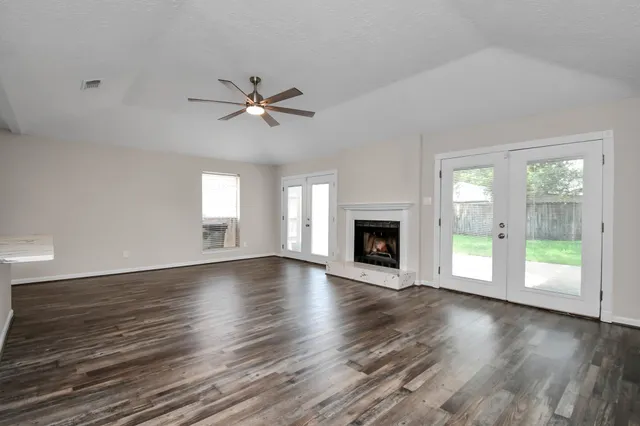 an empty room with wooden floor fireplace and windows