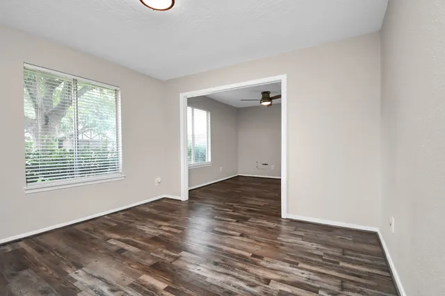 a view of an empty room with wooden floor and a window