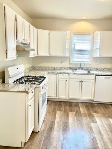 a kitchen with stainless steel appliances granite countertop a stove a sink and white cabinets