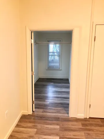 a view of empty room with window and wooden floor