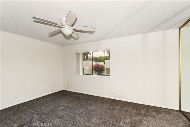 an empty room with windows and fan