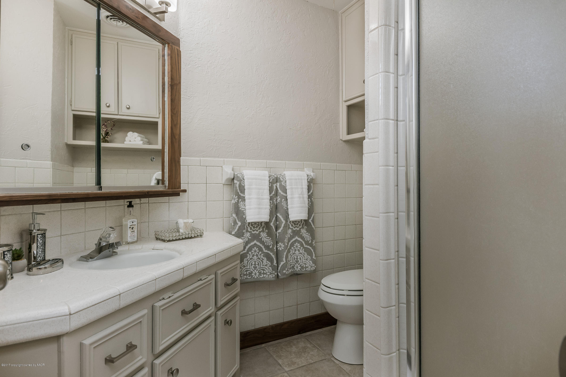 7208 Calumet Road Amarillo, TX 79106 - Photo 15 of 22 a bathroom with a granite countertop toilet a sink and a mirror