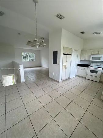 a kitchen with stainless steel appliances kitchen island granite countertop a refrigerator a stove and white cabinets with wooden floor